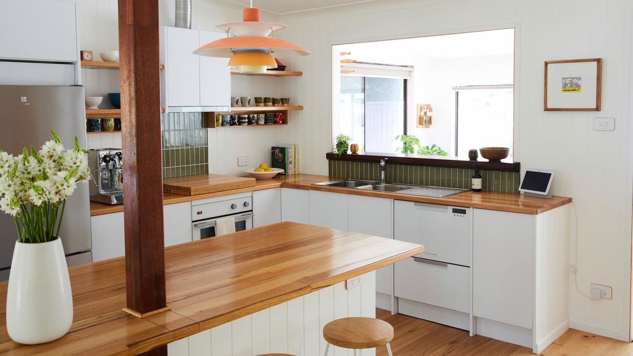 Modern kitchen with wooden bench tops and hanging lights.