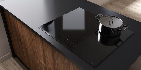 Black stove top with pot, on a black benchtop with dark brown wood-look drawers