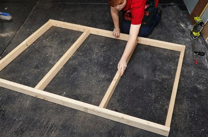 Person laying out pieces of timber that will be used for timber bedhead frame.