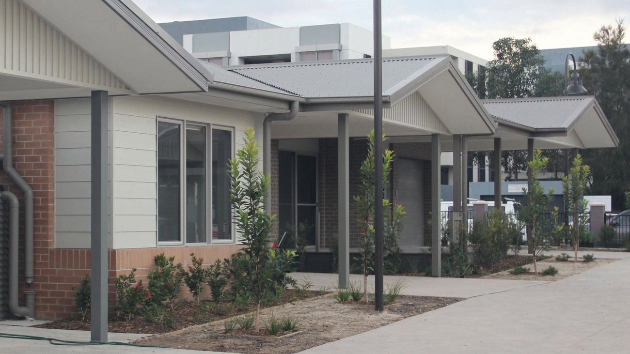 Wide shot of three cottages as part of a retirement complex, with a tree planted in front of each, and a street lamp in front.
