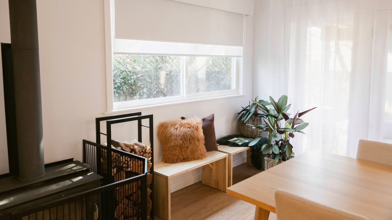 A cozy corner of a living room featuring a bench with cushions underneath the window