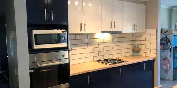 A kitchen with a white tiled splashback and black cabinets