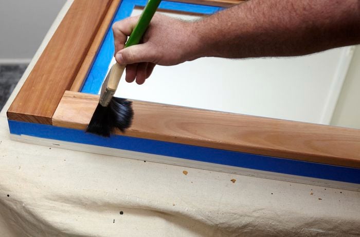 A person varnishing a timber frame with a brush