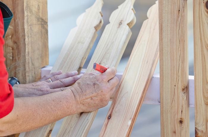 A wooden rail being marked with a pencil and tape measure