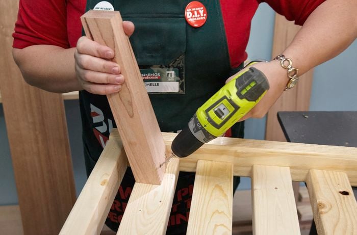 Person drilling timber bed leg into frame