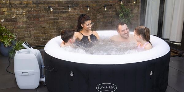 Family sit in a spa bath with in their yard with daughter and son and the front and mother and father at the back