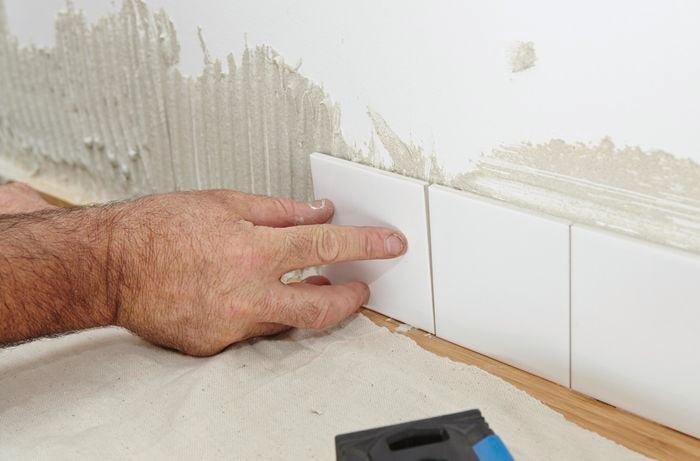 Person laying tiles for kitchen splashback.