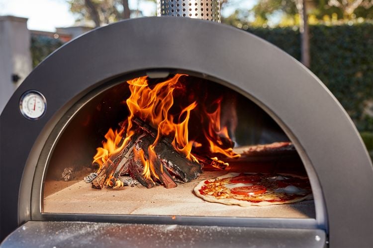 A lit pizza oven cooking a very ordinary looking pizza