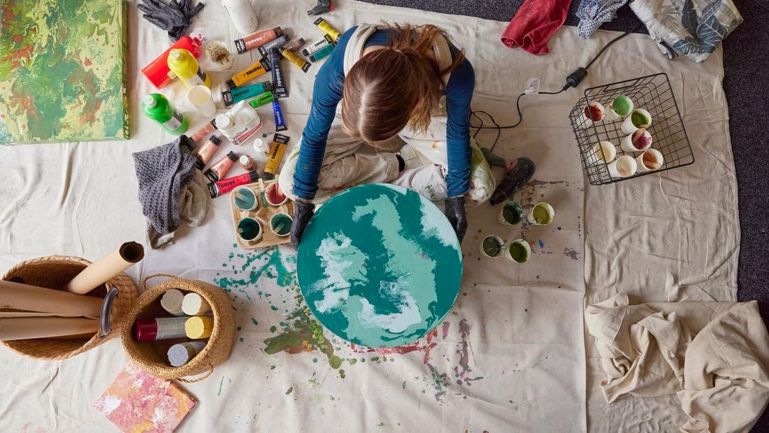 Bella in an art studio holding finished paint pour artwork