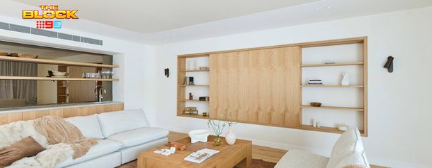 Contemporary living room featuring large neutral sofas, a timber coffee table and built-in timber shelving with concealed storage.