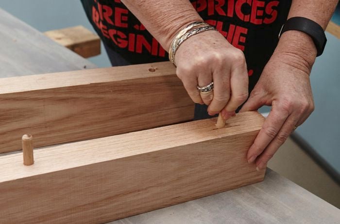 A person inserting dowels into timber