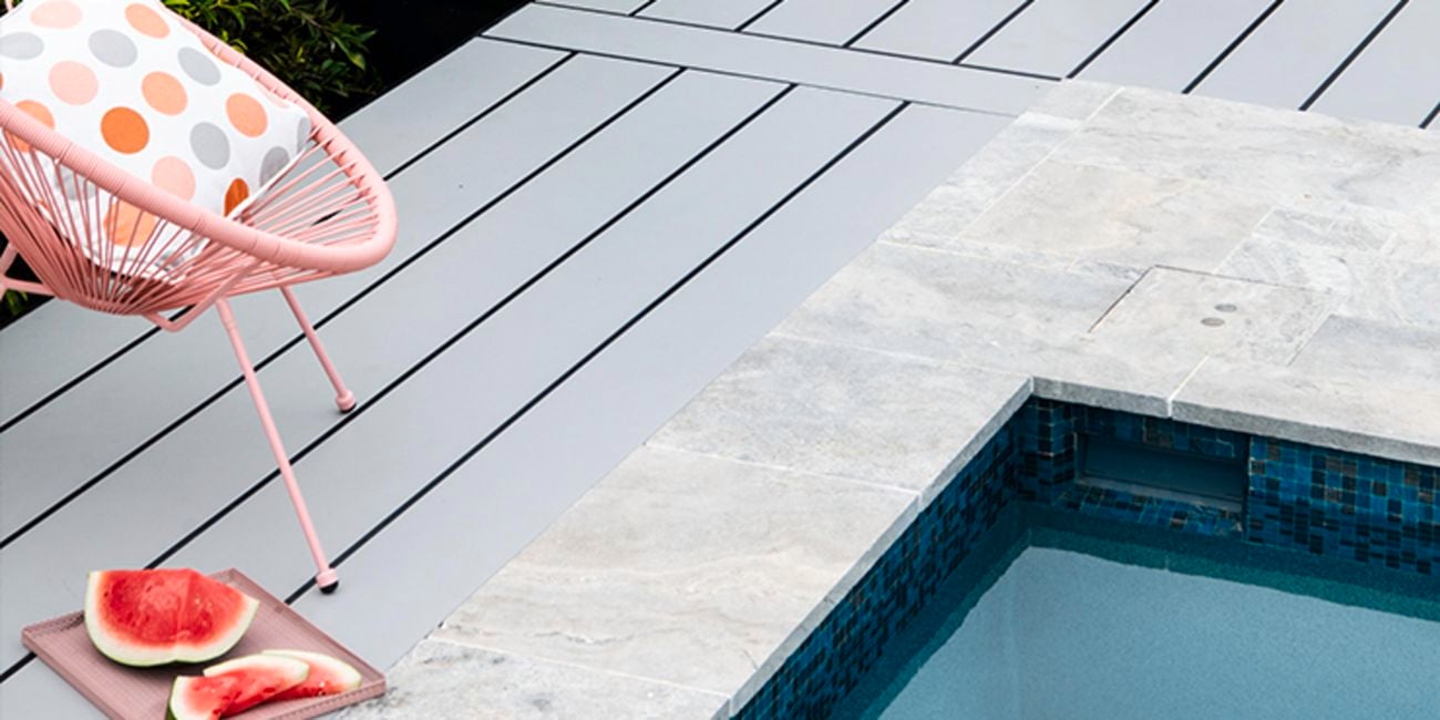 Pool surrounded by timber decking with a pink chair