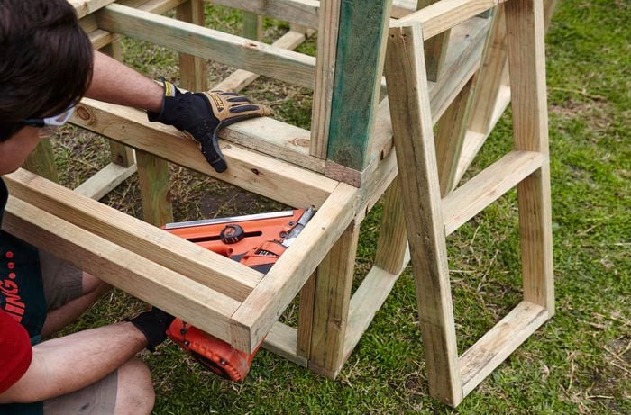 Part of a wooden frame for a chicken coop being nailed into place by a Bunnings team member with a nail gun