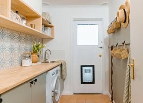 Updated laundry with doggy door, timber bench tops, timber shelving and mosica green and blue wall tiles