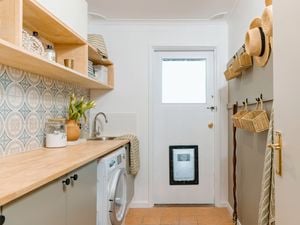 Updated laundry with doggy door, timber bench tops, timber shelving and mosica green and blue wall tiles