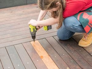 A Bunnings team member repairing a plank of wood on a deck.