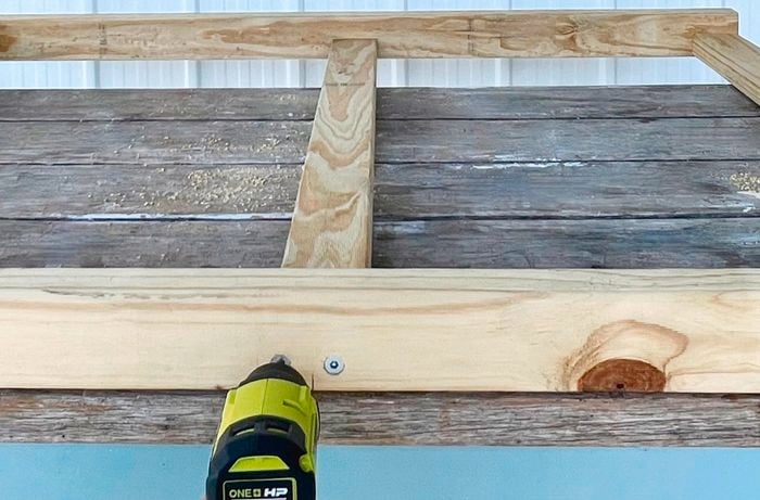 Person attaching a centre rail to a wooden frame with a drill.