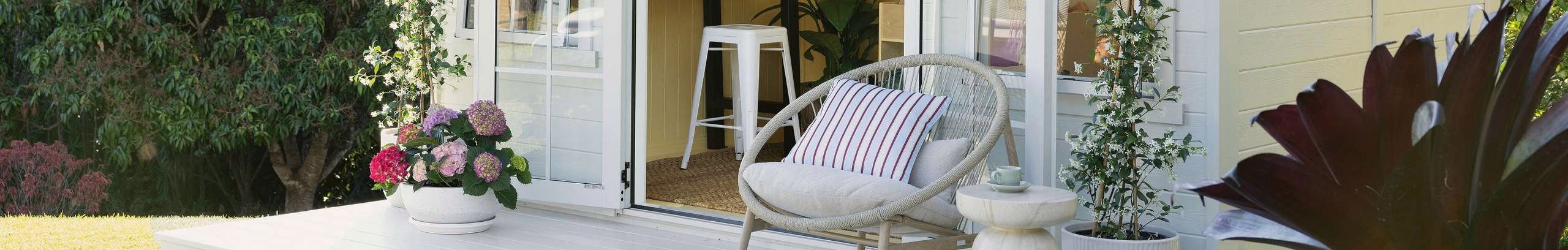 Outdoor chair and outdoor pots with flowers at entrance of a studio.