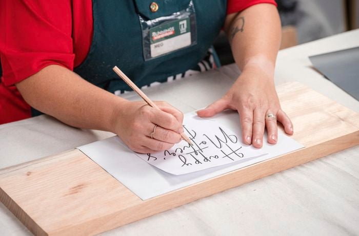 A woman is writing Happy Mother's Day on a paper.
