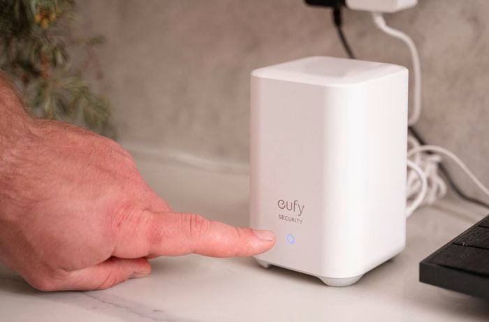 A person directing his finger to a security camera homebase.