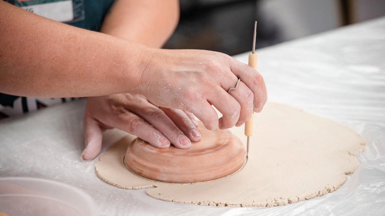 A bunnings team member using a round object to cut out base.