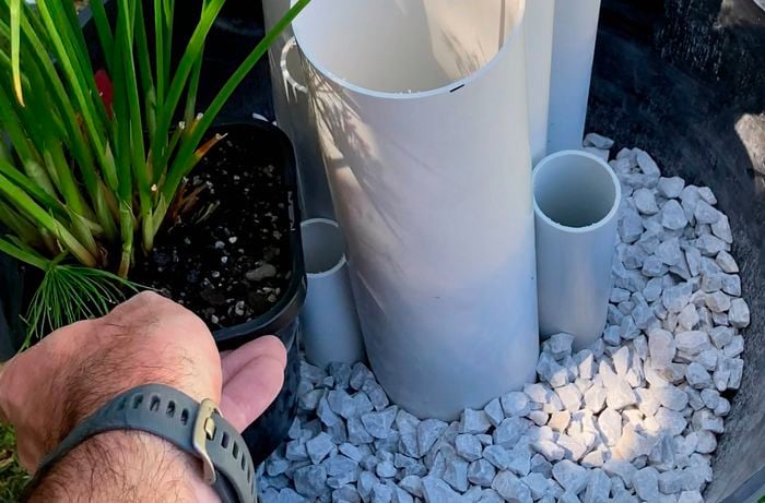 A pot with white pebbles and pvc pipes in it.