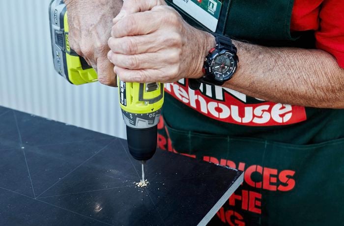 A hole being drilled at the centre of space set aside for a flower pot on a vertical garden tier