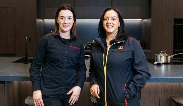 Two ladies standing in a modern kitchen in front of the kitchen bench.