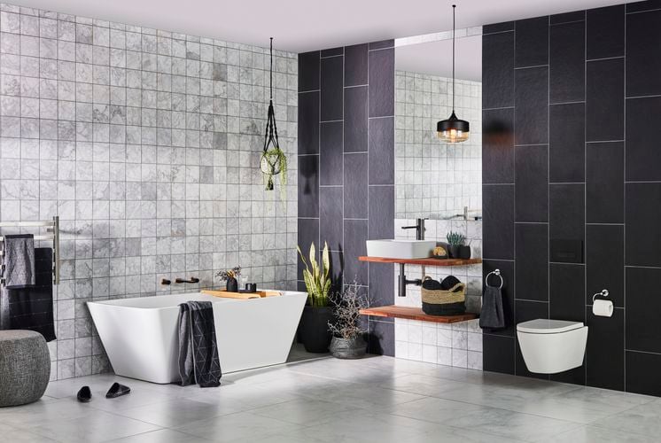 Modern bathroom with black tiles on the wall, white-grey tiles on the floor with a white sink and bath