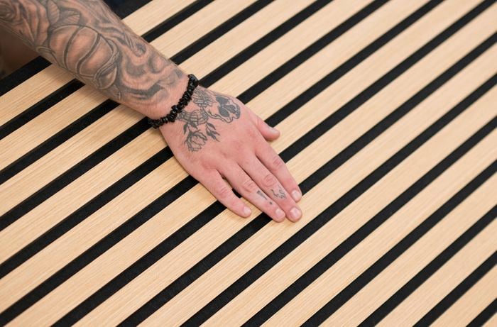 A tattooed hand is touching the timber wood slat.