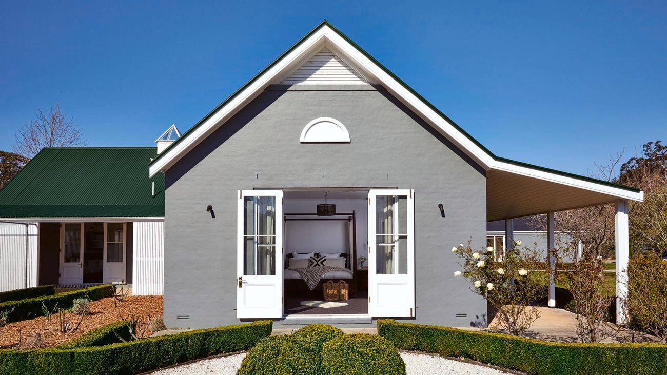 Country style house, with grey frontage and surrounded by greenery schrubs