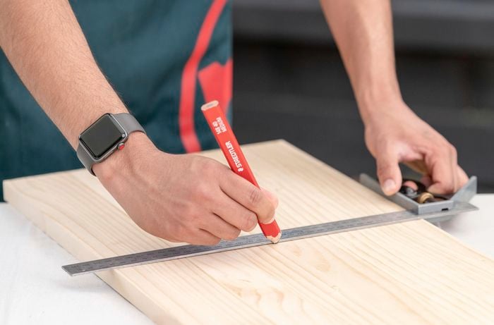 Using a square ruler to mark timber with a pencil
