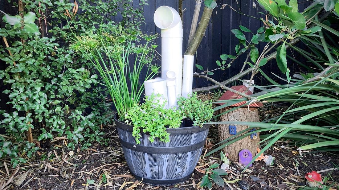 A pot with plants and PVC pipes in it.