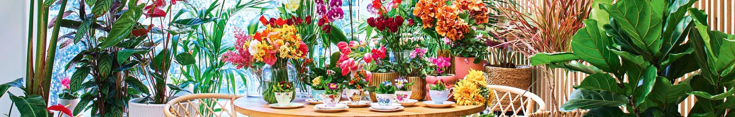 A small round dining table with an abundance of bright florals around it.