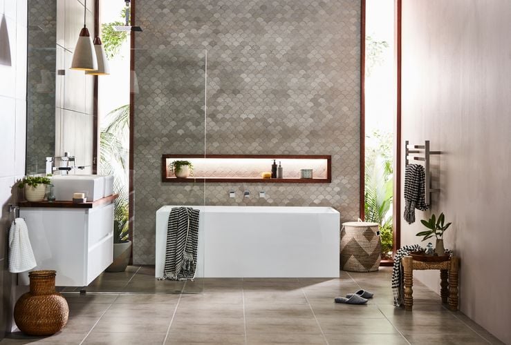 Modern bathroom with grey tiles, white bath and white sink with cabinets