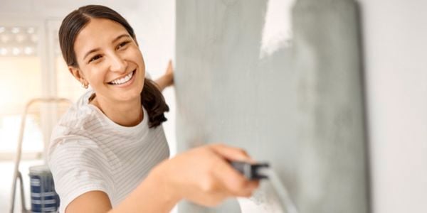 A woman painting a wall with a roller.
