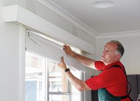 Bunnings team member installing venetian blinds in a lounge room
