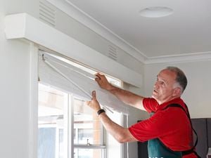 Bunnings team member installing venetian blinds in a lounge room