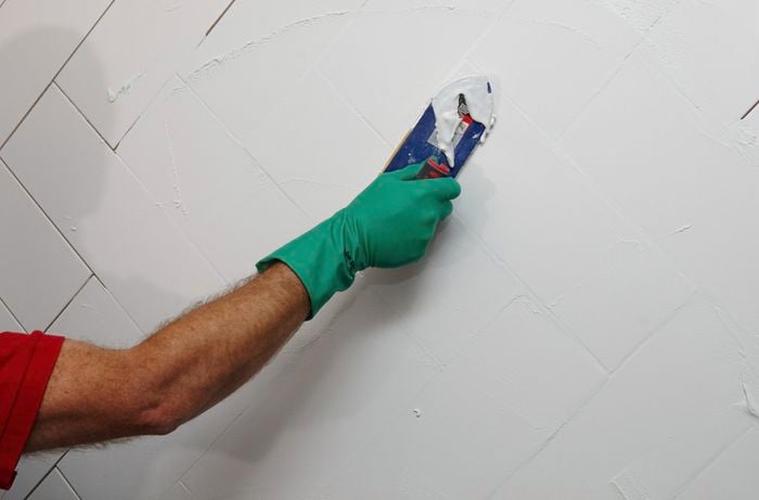 Grout being applied to tiles on a wet wall