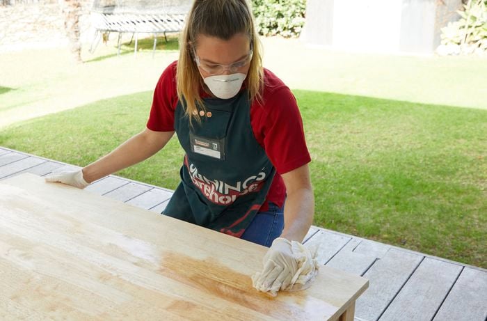 Person applying a coat of furniture oil to a table with a cloth.