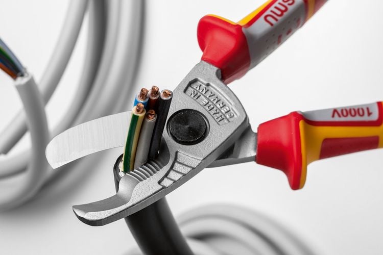 Person cutting copper wiring with cutters