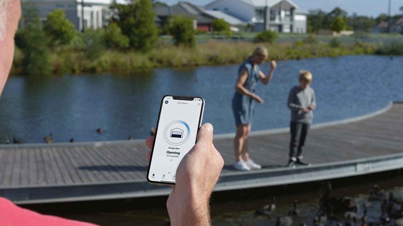 A man looking at a smartphone, while his family is in the background