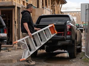 A man putting a ladder in a ute.