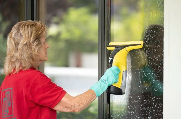  A Bunnings Team Member wearing gloves uses a window vacuum cleaner to remove cleaning solution from a window.