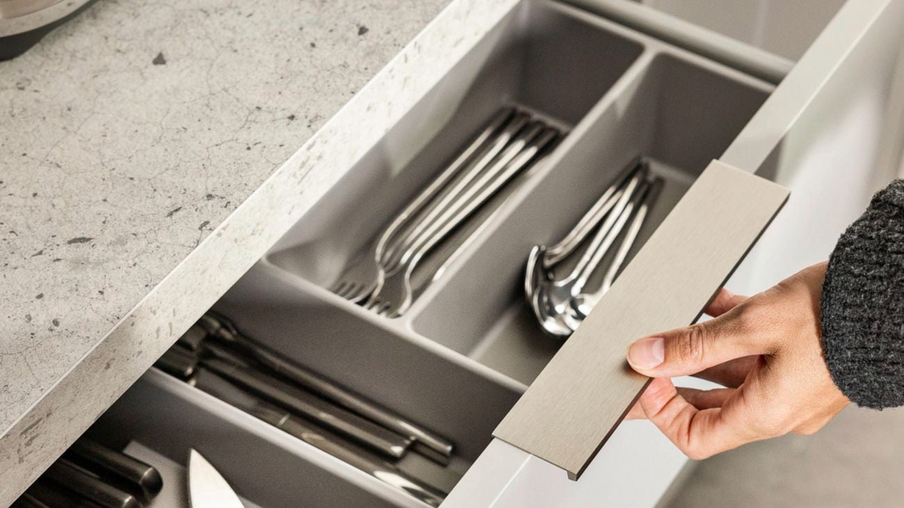 A person opens a kitchen drawer, showing the organised cutlery.