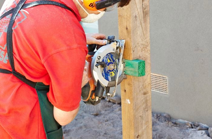 Person using saw to cut off excess plinth.