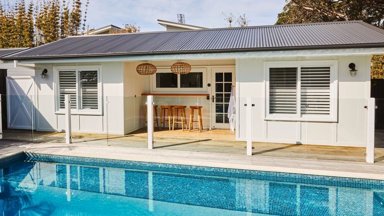 Tiled pool in a backyard, featuring a glass pool fence