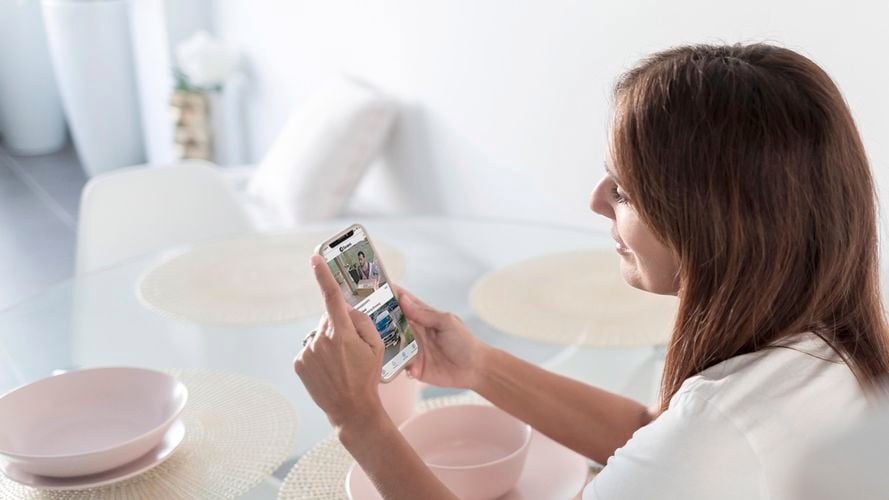 A woman using the app on her phone at the dinner table