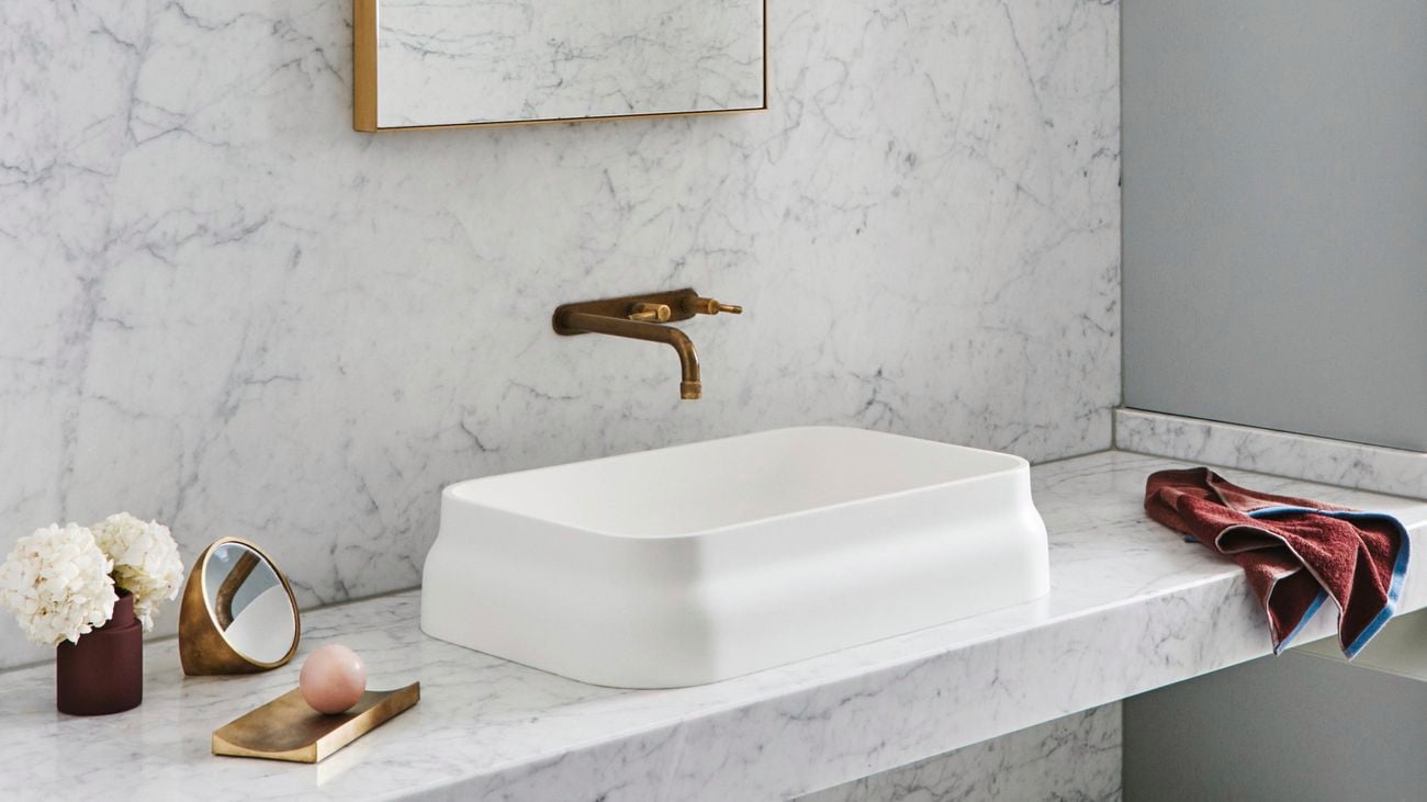 Bathroom with basin, marble surfaces and brass accents.