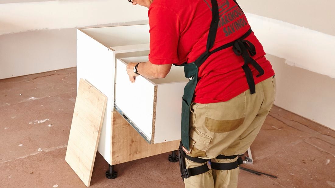 Person removing top drawer of cabinet.